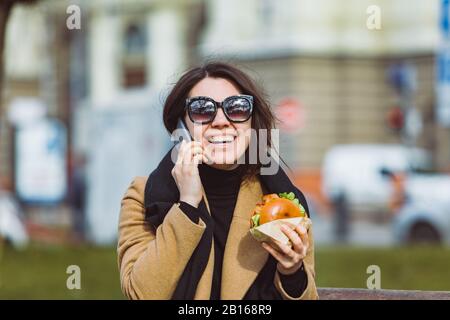 Junge Schönheit Business woman Essen fast food und Arbeiten am Telefon während der Sitzung im City Bank Stockfoto
