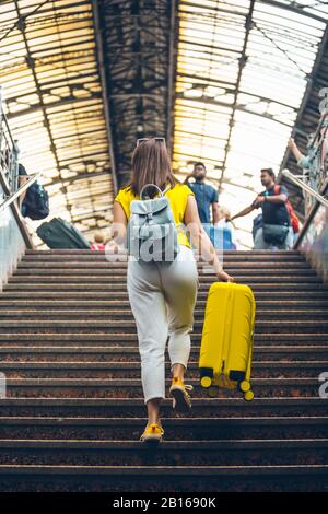 Frau mit gelber Tasche, die am Bahnhof über eine Treppe hinaufgeht Stockfoto