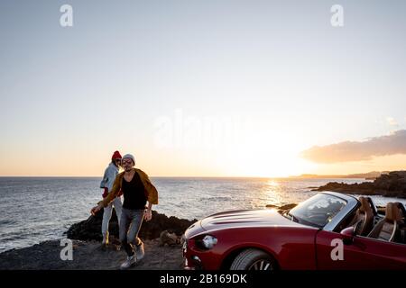 Ein Paar, das zusammen Spaß hat, während der Fahrt mit dem Auto an der felsigen Küste Landschaften genießt, einen weiten Blick von der Seite mit Copy-Platz am Himmel Stockfoto