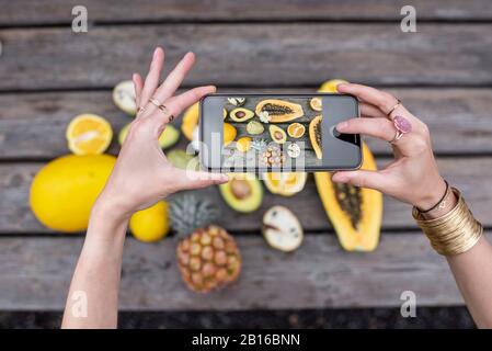 Porträt einer jungen lächelnden Frau mit geschnittener Papaya-Frucht und Avocado-Beere im Freien auf der tropischen Plantage. Konzept von Vegetarismus, gesundem Essen und Wohlbefinden Stockfoto