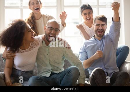 Aufgeregte überfreudige Freunde, die mit Freude den Sieg des Sportteams feiern Stockfoto