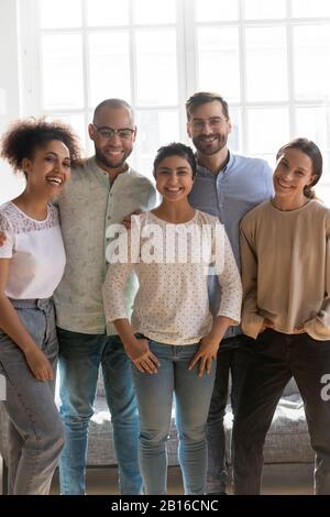 Vertikale Ansicht fünf multiethnische Freunde, die sich in Innenräumen aufsetzen Stockfoto