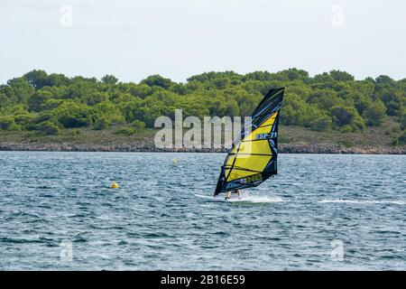 Menorca, Spanien - 12. Oktober 2019: Windsurfer surfen auf den Wellen des blauen Meeres. Stockfoto