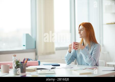 Seitenansicht Porträt der freckenden jungen Frau Tagträumen in modernen Büros beim Kaffeetrinken am Arbeitsplatz, Kopierraum Stockfoto