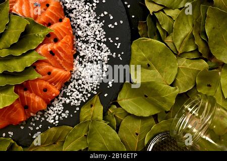 Schneiden Sie frisch gesalzene rote Fische in Scheiben mit grobem Lorbeerblattsalz und schwarzen Pfeffererbsen in einem Mixbecher. Stockfoto