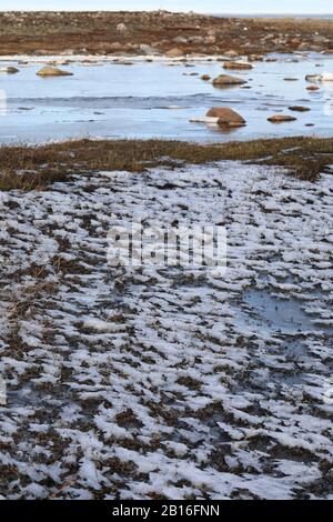 Arktische Landschaft mit Eis am Rande eines kleinen Stroms mit Felsen, die belichtet sind, in der Nähe von Arviat Nunavut Kanada Stockfoto