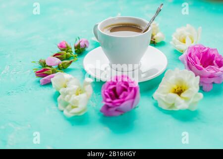 Flache Laienzusammensetzung mit Frühlings-Ranunculus-Blumen und Tasse Kaffee auf Farbhintergrund. Leerzeichen für Text Stockfoto