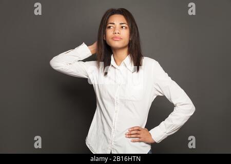 Denken Sie daran, an schwarze Frauen zu zweifeln, die in einem weißen Hemd auf grauem Hintergrund sind Stockfoto