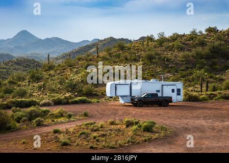 Weißer Wohnmobile und schwarzer Lastwagen parkten auf einer schmutzigen Straße in der Sonoran-Wüste in Arizona. Stockfoto