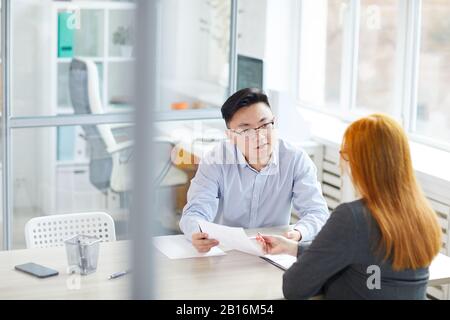 Portrait junger asiatischer Unternehmer, der junge Frau für eine Anstellung in einem modernen Büro interviewt, Copy-Space Stockfoto