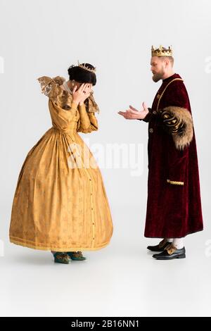 König mit Krone und weinender Königin auf grauem Hintergrund Stockfoto