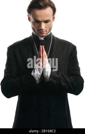 Seriöse katholische Priester, die mit verbeugtem Kopf auf Weiß betten Stockfoto