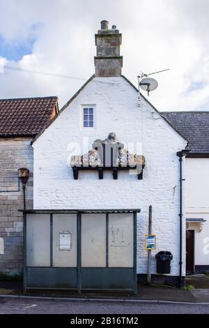 3 Löwen eine Skulptur, die von einer Wand aus einer Kneipe vorkragt, genannt die 3 Löwen mit einer Bushaltestelle vor dem Dorf holt in Wilt Stockfoto