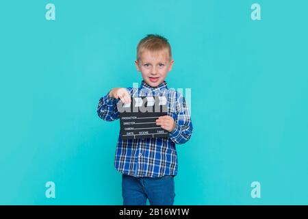 Lächelndes Kind, das Filmklapper auf blauem Hintergrund hält Stockfoto