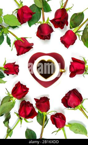 Rote Rosen kreative Komposition flacher Lay Layout mit Kaffee in herzförmiger Tasse und Untertasse auf weißem Hintergrund. Stockfoto