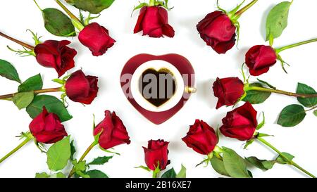 Rote Rosen kreative Komposition flacher Lay Layout mit Kaffee in herzförmiger Tasse und Untertasse auf weißem Hintergrund. Stockfoto