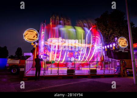 Verschwommene farbige Lichtlinien von der sich schnell bewegenden Fairground Attraktion auf der Sassenheimer Stadtmesse in den Niederlanden. Stockfoto