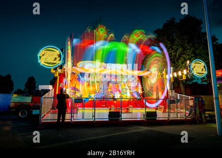Verschwommene farbige Lichtlinien von der sich schnell bewegenden Fairground Attraktion auf der Sassenheimer Stadtmesse in den Niederlanden. Stockfoto