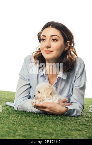 Lächelnde Frau mit Havanese Welpe auf Gras liegend isoliert auf Weiß Stockfoto