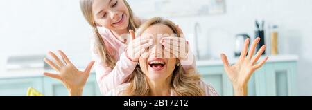 Panoramaaufnahme des glücklichen Kindes, das die Augen der überraschten Mutter bedeckt Stockfoto
