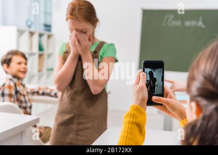 Selektive Fokussierung von Schulmädchen Foto von Mitschüler, Cyberbullying Konzept Stockfoto