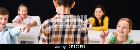 Panoramaaufnahme von Schulkindern, die mit den Fingern auf den Schuljungen zeigen, isoliert auf schwarzem, Mobbingkonzept Stockfoto