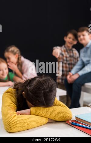 Selektiver Fokus von verärgerter Schulmädchen, die Gesicht in der Nähe von Klassenkameraden bedecken und mit dem Finger auf schwarzem, Mobbingkonzept zeigen Stockfoto