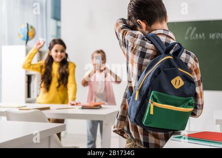 Rückblick auf schikanierte Kinder, die in der Nähe grausamer Klassenkameraden mit Smartphone stehen, Cyberbullying Konzept Stockfoto