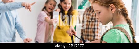 Panoramaaufnahme von Schulkindern, die Schulmädchen im Klassenzimmer anschikanieren Stockfoto
