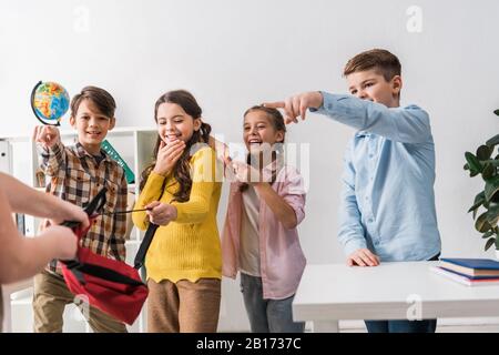 Selektive Fokussierung grausamer Schulkinder, die mit den Fingern auf schikanierte Mitschüler zeigen Stockfoto