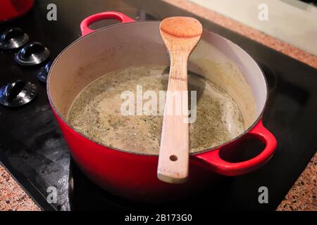 Ein Löffel, der auf einem Topf ruht und darin Suppe kocht Stockfoto