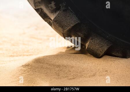 Große schwere Traktorreifen auf weichem Boden wie Strandsand (Kopierraum) Stockfoto