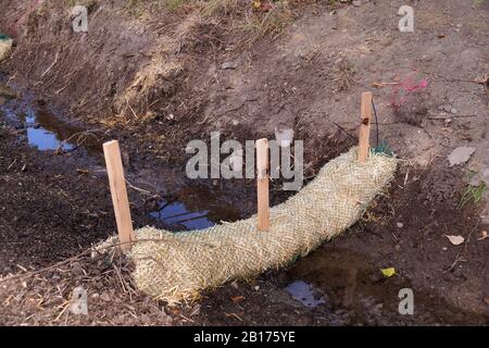 Landabflussarbeiten. Die Verwendung von Strohwatten (Strohwürmer, Biostämme, Strohnudeln). Stockfoto