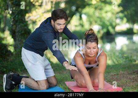 Junges Paar mit Trainingsmatten neben einem Baum Stockfoto
