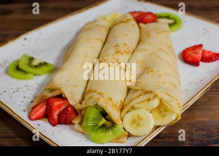 Gesunde Crepes mit Früchten, Bananen, Kiwi und Erdbeere. Gesundes französisches Frühstück Stockfoto