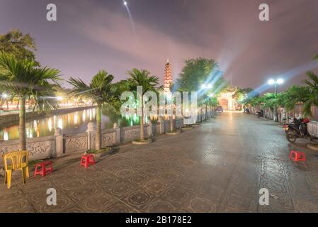 Fassadeneingang des buddhistischen Tempels Tran Quoc Reflexion am Westsee in Hanoi in der Nacht Stockfoto