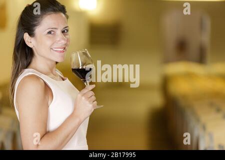 Frau mit einem Glas Wein im Keller Stockfoto