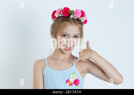 Süßes Mädchen, das mir Handzeichen zeigt, ruft mich an. Nahaufnahme des kaukasischen Kindermodells mit geblümtem Kopfband, isoliert auf weißem grünem grauen Cop Stockfoto