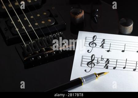 Musik Hinweis und Vintage pen auf Schwarz E-Gitarre in der Dunkelheit. Konzept der Rockmusik kreativ. Stockfoto