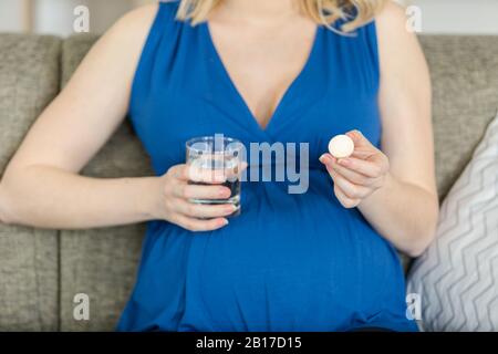 Schwangere Frau, die Pillen nimmt, um Schmerzen zu lindern Stockfoto