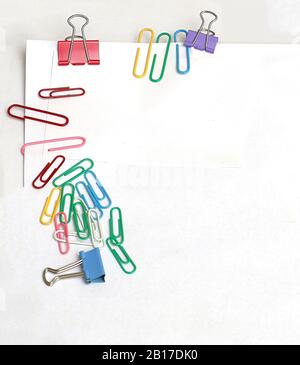 Bunte Metall-Stationärgeräte Papier und Binder Clips an der Papierkante Stockfoto