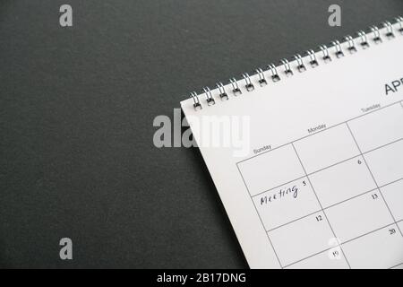 Weißer, sauberer Kalender auf schwarzem Hintergrund mit Kopierbereich. Wörter. Besprechung neben einem Datum. Konzept für Geschäftstreffen und -Termine. Stockfoto