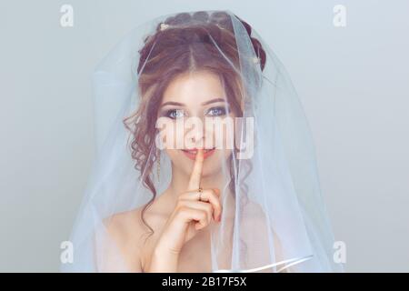 Bride Shh Frau weitäugig bitten um Schweigegeheimnis mit Finger auf den Lippen Hush Hand Geste weiß Stockfoto