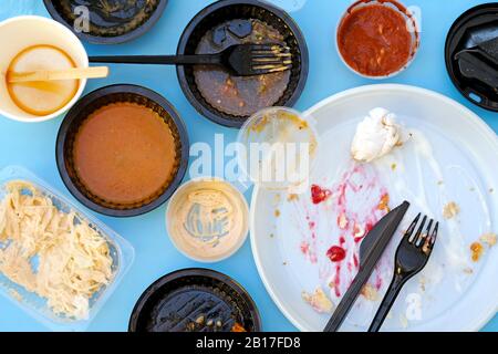 Leere schmutzige Plastikgerichte nach dem Abendessen. Gebrauchte Kunststoffschalen, Draufsicht. Teller, Schüsseln, Gabeln und ein Messer aus Kunststoff nach Gebrauch. Schnelles Mittagessen in einer fas Stockfoto