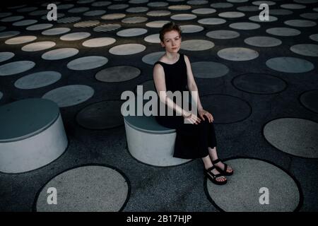 Elegante Frau auf einer runden Bank in futuristischer Architektur Stockfoto