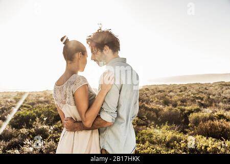 Liebevolles junges Paar umarmt an der Küste im Sommer Stockfoto