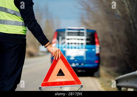 Mann setzt Warndreieck auf Landstraße durch van Pannenfall Stockfoto