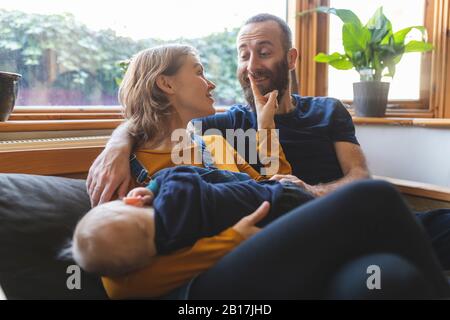 Glückliche Familie auf dem Sofa mit schlafenden kleinen Sohn Stockfoto