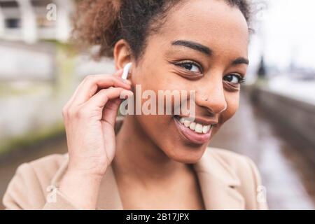 Porträt einer lächelnden jungen Frau mit Ohrstöpseln Stockfoto