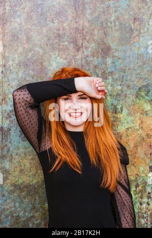 Porträt von glücklichen rothaarigen jungen Frau in schwarz gekleidet Stockfoto